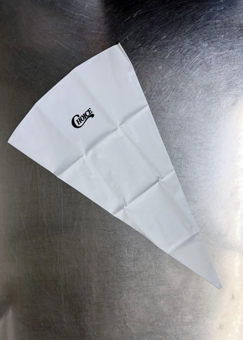Empty reusable Choice brand piping bag laid flat on a stainless steel surface, used for decorating cakes, filling pastries, or precise food presentation.